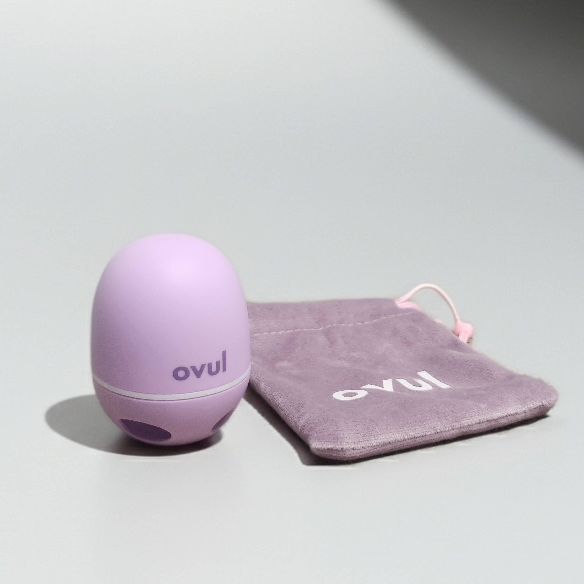 Ovul fertility tracker with purple travel pouch on gray background
