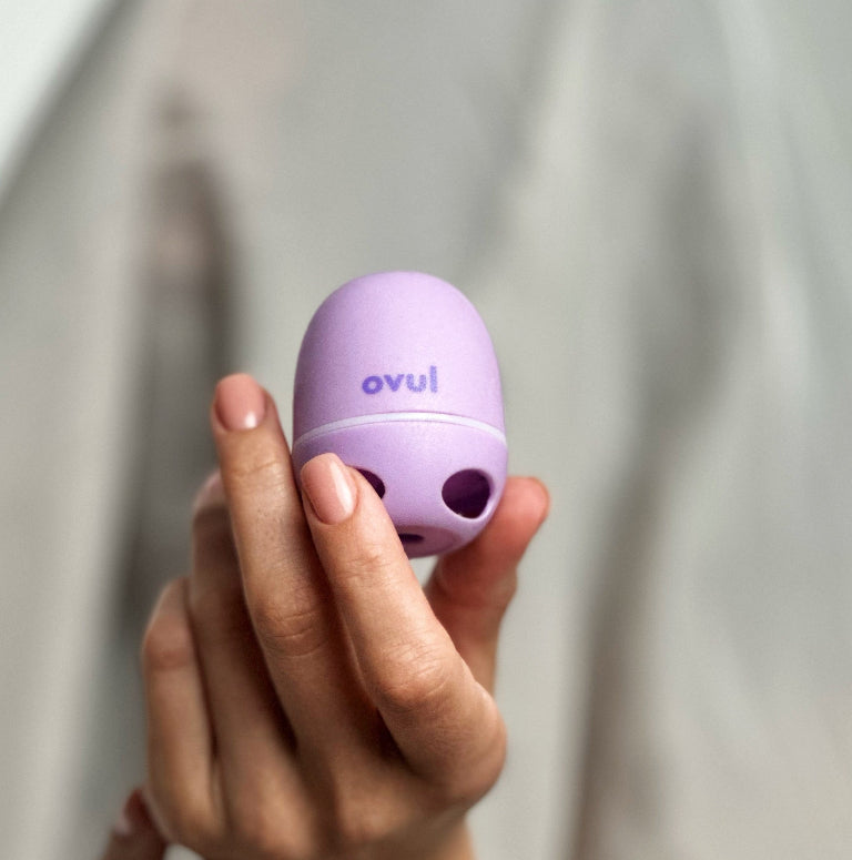 Woman's hand holding Ovul ovulation tracker for at-home saliva-based hormone testing and monitoring